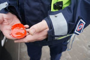 policjant trzyma breloki odblaskowe