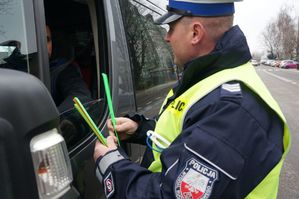 policjant wręcza kierującemu opaski odblaskowe