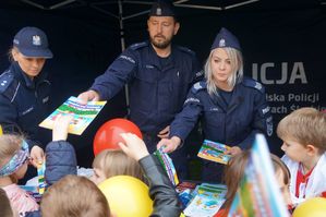 policjanci rozdają książeczki edukacyjne dzieciom