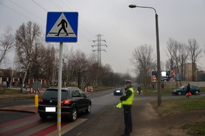 policjant stoi przy oznakowanym przejściu dla pieszych