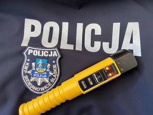Zdjęcie poglądowe urządzanie do badania zawartości alkoholu w wydychanym powietrzu na tle logo Komendy Policji Siemianowice Sląskie