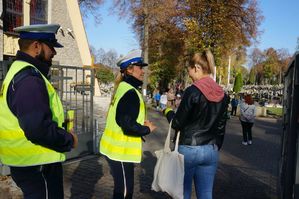 policjanci rozdają opaski odblaskowe przy cmentarzu