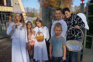 dzieci przebrane za anioły z odblaskami i koszykiem z cukierkami przy cmentarzu
