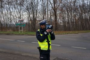 na zdjęciu policjant z radarem mierzy prędkość jazdy