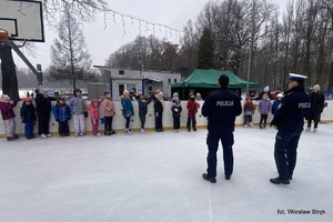 na zdjęciu policjanci stoją przed dziećmi na lodowisku
