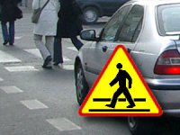 na zdjęciu znak drogowy ostrzegawczy przejście dla pieszych, w tle samochód