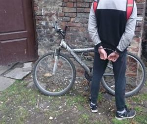 na zdjęciu zakuty w kajdanki złodziej obok skradzionego roweru