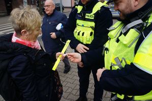 na zdjęciu policjanci wręczają kobiecie opaskę odblaskową i brelok