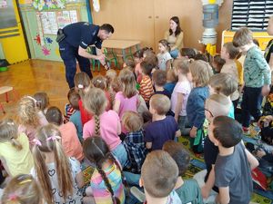 na zdjęciu policjant pokazuje dzieciom książeczkę