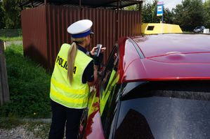 na zdjęciu policjantka pokazuje kierowcy radar z nagraniem przekroczenia prędkości jazdy