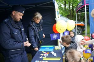 na zdjęciu dzieci przy stanowisku profilaktycznym z policjantem i strażniczką miejską