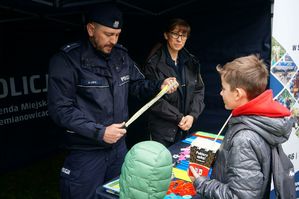 na zdjęciu policjant wręcza odblaskową smycz dzieciom ze strażniczką miejską