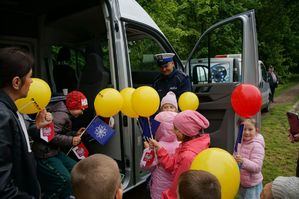 na zdjęciu policjant z drogówki z dziećmi z balonami przy radiowozie