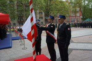 strażacy z flagą przy maszcie