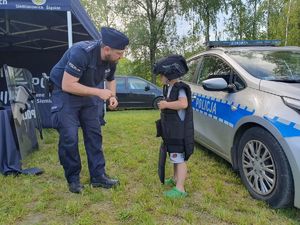 na zdjęciu policjant stoi z dzieckiem ubranym w tarczę i kask