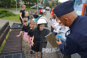 na zdjęciu policjant z tarczą i dzieci