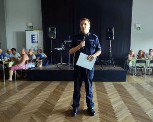 na zdjęciu policjant stoi i przemawia