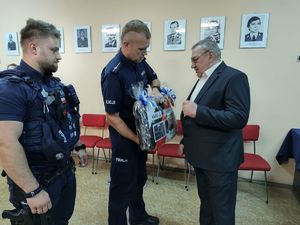 na zdjęciu policjanci wręczają Panu Leonowi Szudydze upominek