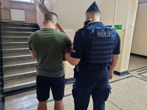 na zdjęciu stoi policjant z zatrzymanym