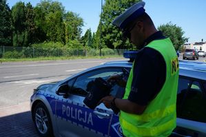 na zdjęciu policjant stoi przy radiowozie z radarem