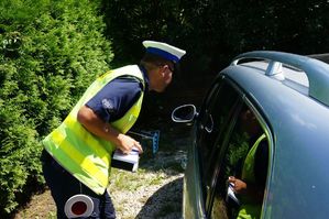 na zdjęciu policjant stoi przy kontrolowanym aucie