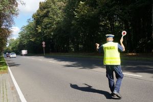 na zdjeciu policjant na drodze daje sygnał kierującemu do zatrzymania się