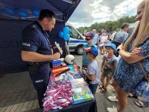 na zdjęciu policjant rozdaje dzieciom gadżety profilaktyczne