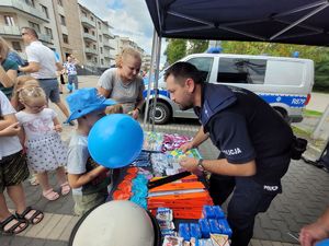 na zdjęciu policjant rozdaje dzieciom gadżety profilaktyczne