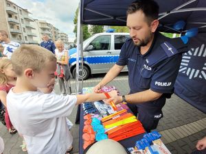 na zdjeciu policjant zakłada dziecku opaskę odblaskową