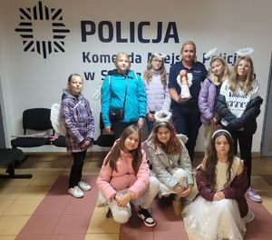 na zdjęciu dzieci z policjantką trzymającą figurkę anioła