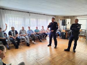 na zdjęciu policjanci stoją przed podopiecznymi i opowiadają