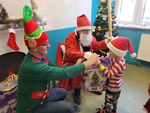 na zdjęciu Mikołaj i elf rozdają prezenty