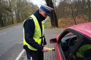 na zdjęciu policjant przy samochodzie z alkomatem