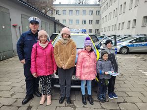 na zdjęciu dzieci stoją z policjantem przy radiowozie