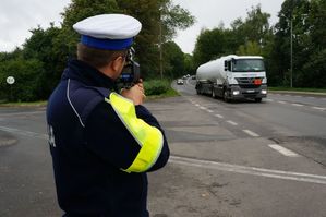 na zdjęciu policjant z drogówki mierzy prędkość jazdy ciężarówki