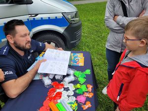 na zdjęciu policjant daje dziecku książeczkę edukacyjną