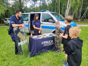 na zdjęciu policjant i strażniczka na stanowisku profilaktycznym z dziećmi