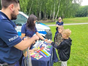 na zdjęciu policjant i strażniczka miejska na stanowisku profilaktycznym z dziećmi