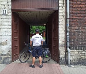 na zdjęciu dzielnicowy na rowerze przy bramie