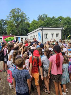 na zdjęciu policjant stoi pośród grupy półkolonistów