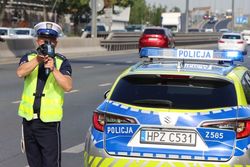 na zdjęciu policjant z radarem obok radiowozu