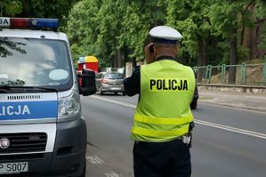 na zdjęciu policjant ruchu drogowego przy radiowozie