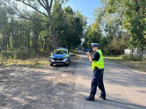 na zdjęciu radiowóz i policjant mierzący radarem