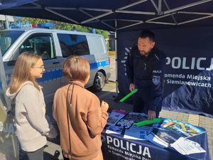 na zdjęciu policjant wręcza dzieciom odblaski