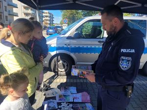 na zdjęciu policjant wręcza książeczkę edukacyjną