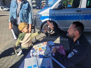 na zdjęciu policjant przebija &quot;piątkę&quot; z dzieckiem