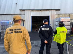 na zdjęciu strażak, policjant i straż miejska stoją przed wejściem do hali