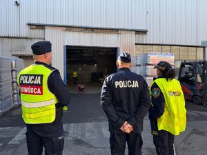 na zdjęciu policjanci i straż miejska stoją przed wejściem do hali