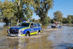 na zdjęciu policyjny suv jedzie po zatopionej ulicy