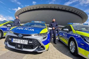 na zdjęciu policjant obok radiowozu, w tle spodek